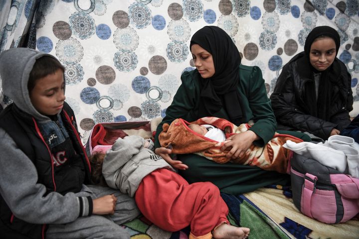 南部ラファのテントの中で1週間前に生まれた赤ちゃんを抱くサブリーン・アル・アザミさん。妊娠7カ月の時にガザ北部ベイトラヒアから避難しなければならず、健康上の問題を抱えながらテントで厳しい生活を強いられている（2023年12月23日）