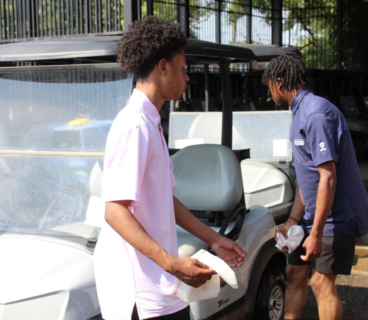Interns clean golf carts as part of their daily tasks.