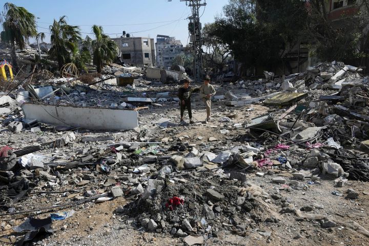 Palestinians walk through destruction from the Israeli bombardment in the Nusseirat refugee camp in Gaza Strip, Friday, Jan. 19, 2024. (AP Photo/Adel Hana)