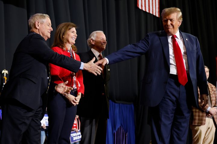 Former President Donald Trump, right, shakes hands with Rep. Joe Wilson (R-S.C.) as a group of South Carolina politicians join Trump on stage in Manchester, New Hampshire. 