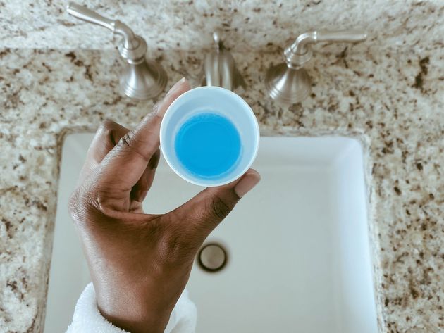 Close-up of woman's hand holding cup of mouthwash