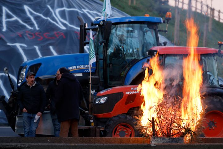 Aγρότες συνομιλούν δίπλα σε μια φωτιά καθώς αποκλείουν έναν αυτοκινητόδρομο κοντά στο Ableiges, βόρεια του Παρισιού, Παρασκευή 26 Ιανουαρίου 2024