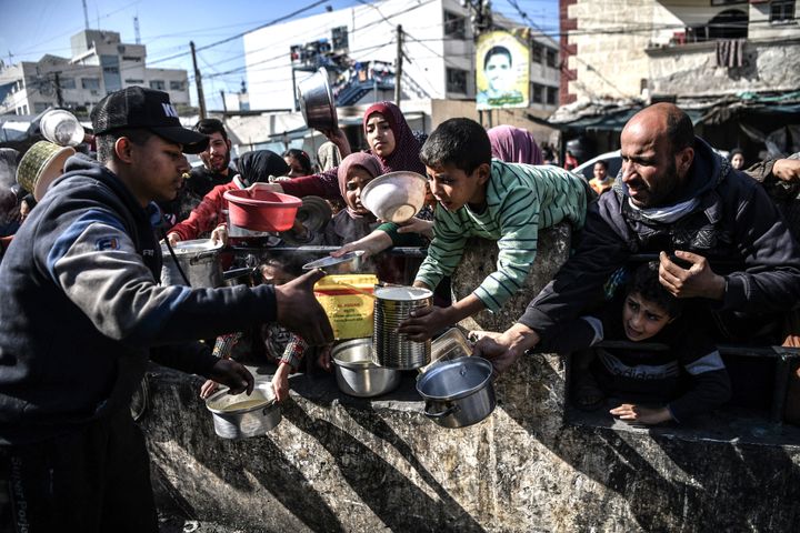 RAFAH, GAZA - JANUARY 25: Palestinian people reach out for food with empty containers as food is distributed by charitable organizations while Israeli attacks continue in Rafah City of Gaza on January 25, 2024. (Photo by Abed Zagout/Anadolu via Getty Images)