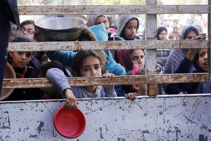 Palestinians, including children struggling with starvation, are seen waiting in front of the food aid stand to receive food distributed by charity organizations, amid ongoing Israeli attacks in Deir Al Balah, Gaza on January 28, 2024.