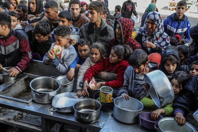 ガザ南部の都市ラファで、ボランティアから配られた食料に手を伸ばすパレスチナの人々。国連パレスチナ難民救済機関（UNRWA）は、イスラエルの攻撃が続く中、ガザ市民が深刻な食糧不足に陥っていると警告している（2024年1月26日）