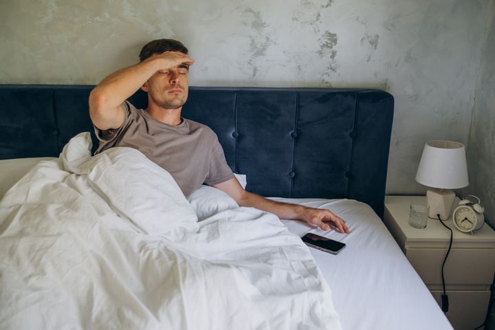 man in bed with migraine headache after a sleepless night