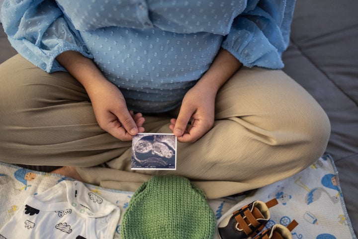 Pregnant woman looking at ultrasound results in the bed at home