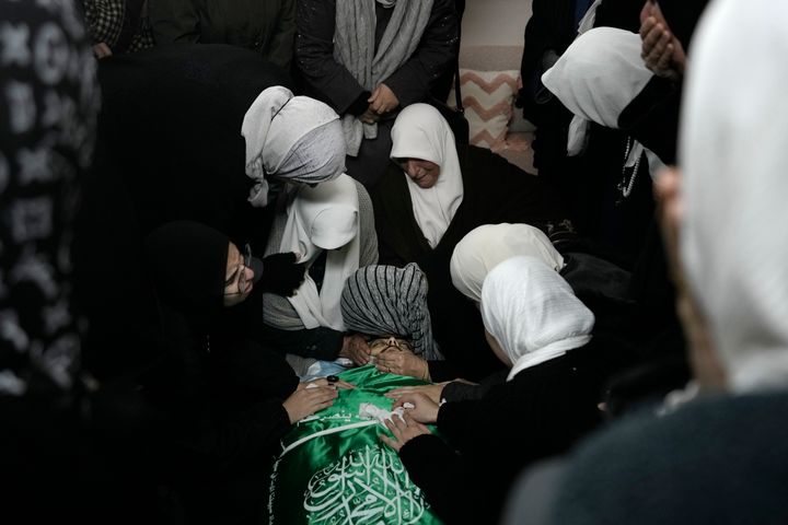 Palestinian women gather around the body of Muhammad Jalamneh, draped in the Hamas militant group flag, in the morgue of Ibn Sina Hospital after he was killed in an Israeli military raid in the West Bank town of Jenin on Jan. 30, 2024.