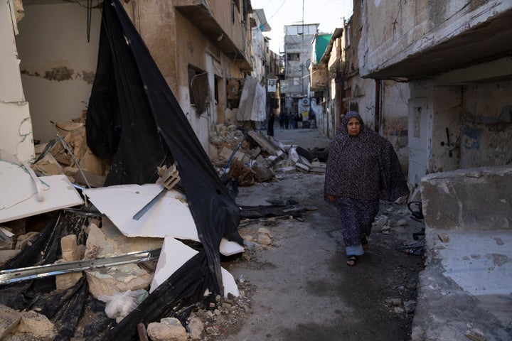 A Palestinian refugee walks past a destroyed houses in the West Bank refugee camp of Tulkarem, Friday, Jan. 19, 2024. (AP Photo/Nasser Nasser)