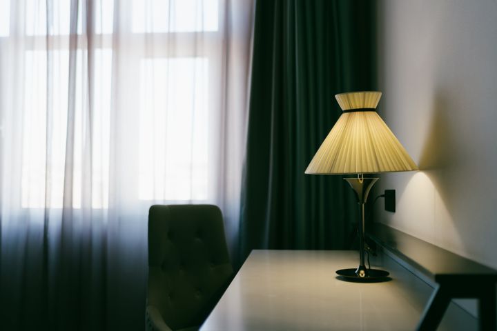The table lamp on the desk next to the window