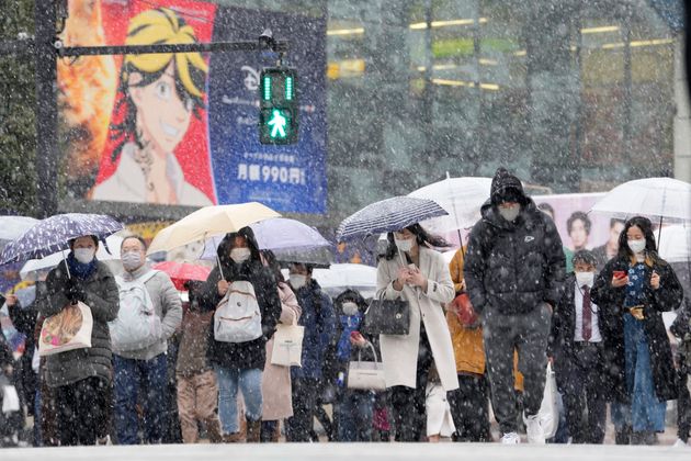 雪が降り積もる中、渋谷のスクランブル交差点を歩いて渡る人々（写真は2022年1月撮影）