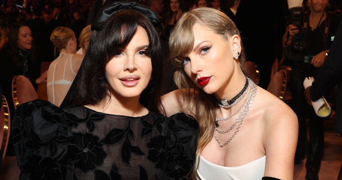 NextImg:Taylor Swift Fixes Lana Del Rey's Red Carpet Look In Adorable Grammys Moment