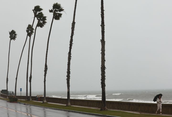 A person walks in the rain as a powerful long-duration atmospheric river storm, the second in less than a week, impacts California on Sunday in Santa Barbara, California. The storm is delivering potential for widespread flooding, landslides and power outages while dropping heavy rain and snow across the region.