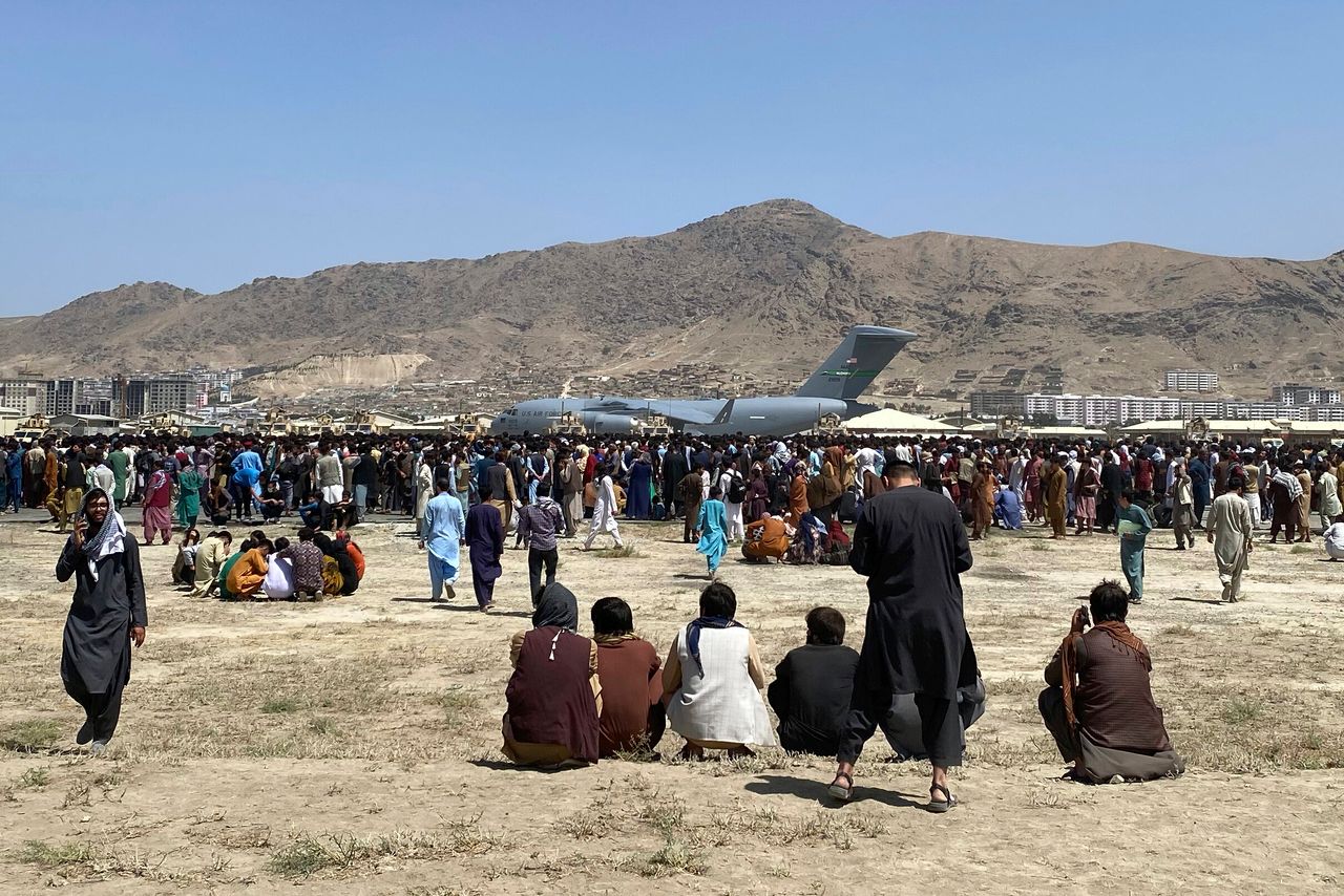 FILE- Hundreds of people gather near a U.S. Air Force C-17 transport plane at the perimeter of the international airport in Kabul, Afghanistan, Monday, Aug. 16, 2021. 