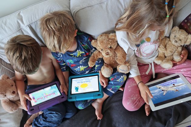 children using computer tablets on sofa