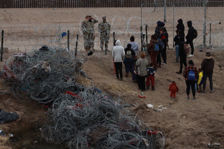 Migrants cross the Mexico border into the U.S. on Tuesday to be received by the U.S. Border Patrol and the Texas National Guard for processing.