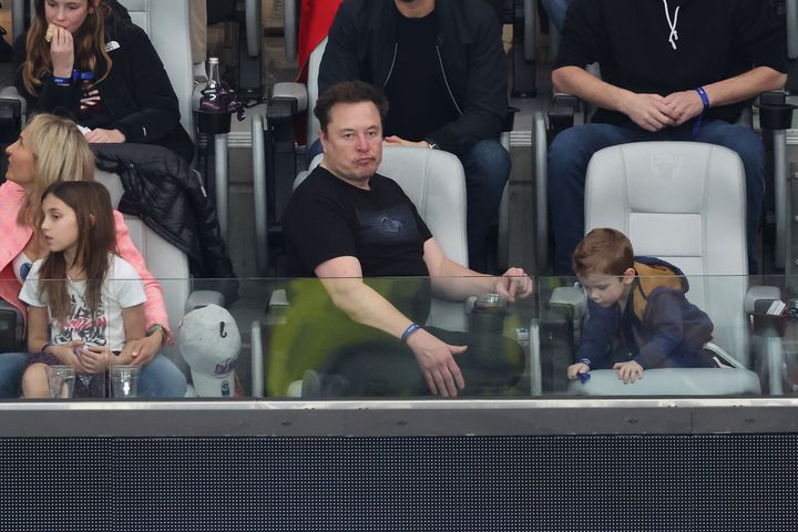Elon Musk looks bored while attending Super Bowl LVIII with his son.