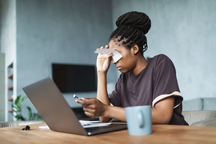 Young black woman calculating utility bills using laptop