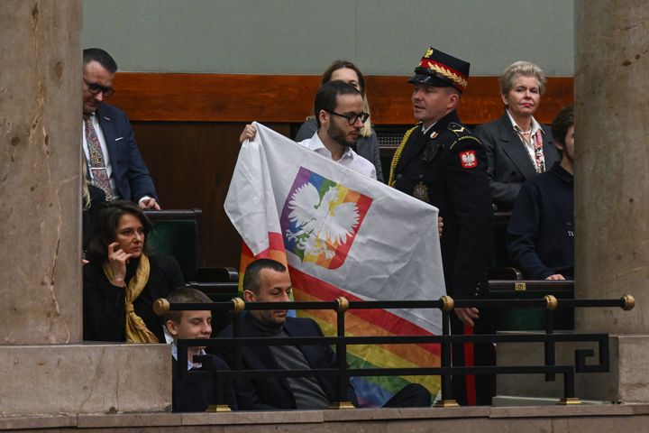 Ο Πολωνός ακτιβιστής των ΛΟΑΤ, Bart Staszewski κρατάει μια σημαία ουράνιου τόξου καθώς ο ηγέτης του Συνασπισμού Πολιτών (ΚΟ), Donald Tusk εκφωνεί ομιλία πριν από την ψηφοφορία για την παροχή ψήφου εμπιστοσύνης στο υπουργικό συμβούλιο της κυβέρνησής του κατά τη διάρκεια συνεδρίασης στο κοινοβούλιο (SEJM) στις 12 Δεκεμβρίου 2023 στη Βαρσοβία, Πολωνία. στις 12 Δεκεμβρίου 2023 στη Βαρσοβία, Πολωνία.