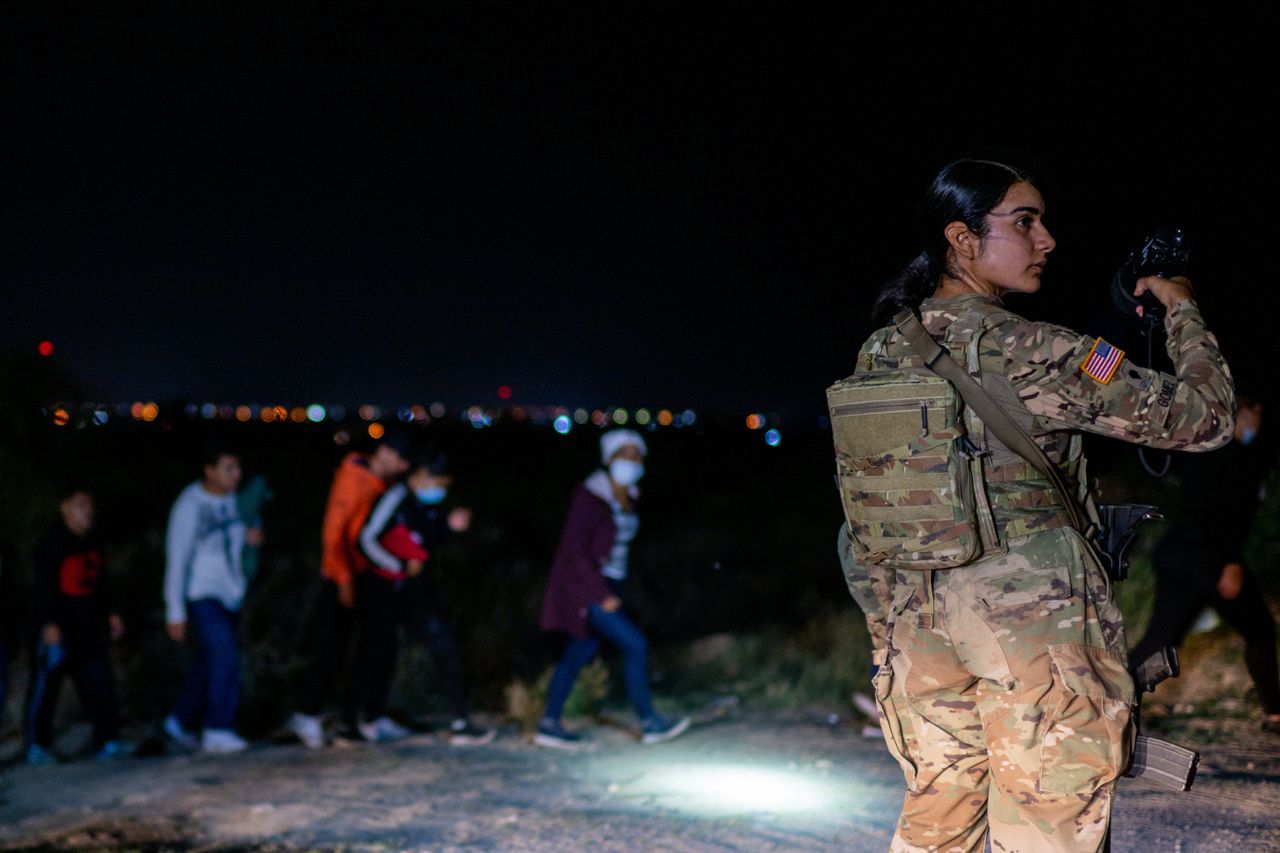 A National Guard officer looks around at migrant families as more migrants arrive after crossing the Rio Grande into the U.S. on May 5, 2022, in Roma, Texas.