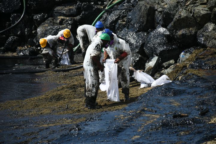 Employees of the national Heritage Oil and Gas Company clean up a spill that reached Rockley Bay Beach in southwestern Tobago on February 11.