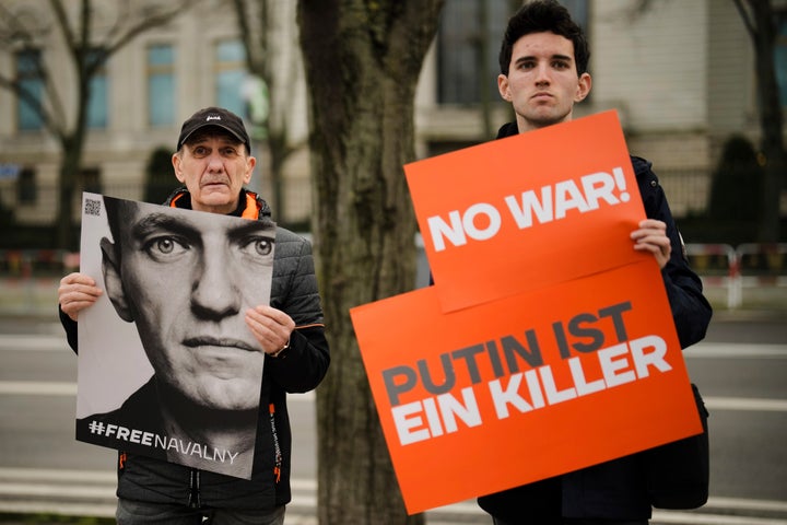 Protesters hold posters with a portrait of Navalny and a sign that reads "Putin is a killer" during a protest in front of the Russian embassy in Berlin on Friday.