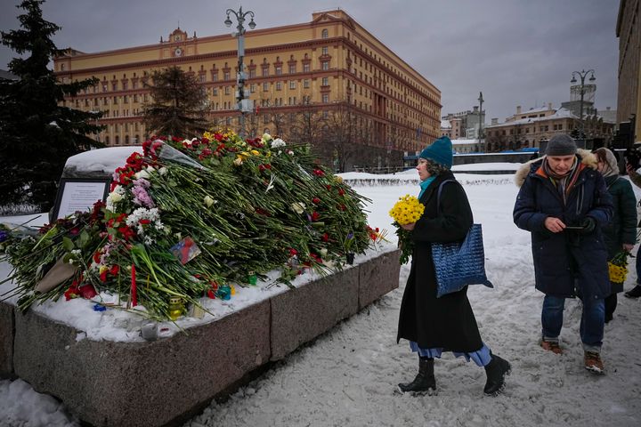 People lay flowers paying the last respect to Alexei Navalny at the monument, a large boulder from the Solovetsky islands, where the first camp of the Gulag political prison system was established, with the historical the Federal Security Service (FSB, Soviet KGB successor) building in the background, in Moscow, Russia, on Saturday morning, Feb. 17, 2024. Russian authorities say that Alexei Navalny, the fiercest foe of Russian President Vladimir Putin who crusaded against official corruption and staged massive anti-Kremlin protests, died in prison. He was 47. (AP Photo/Alexander Zemlianichenko)