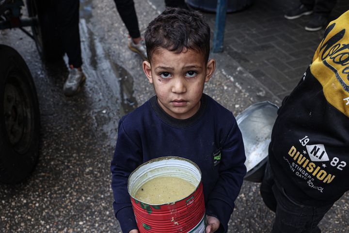 A displaced Palestinian child carries a ration of red lentil soup, distributed by volunteers in Rafah in the southern Gaza Strip on February 18, 2024. After more than four months of war that has flattened huge swathes of the strip, Gazans are inching closer towards famine, according to the UN's World Food Program.