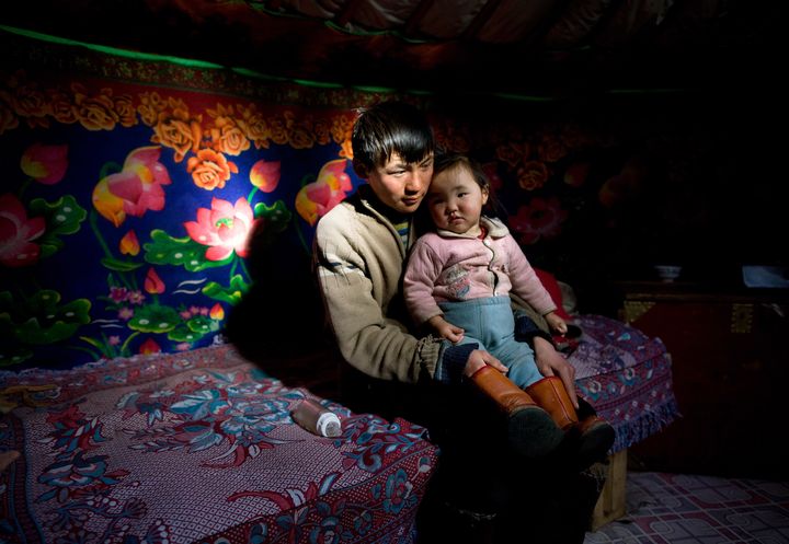 A 17-year-old Mongolian herder, Sukhbaatar, sits with niece Altantsetseg inside their "ger," a traditional nomadic home sometimes called a "yurt" in English.