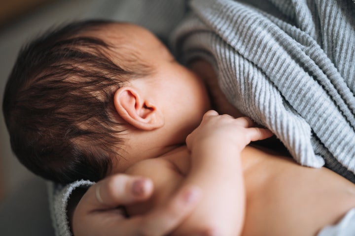 Young mother breastfeeding your newborn baby boy at home