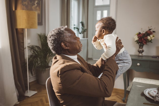 Proud Grandfather Cuddling Baby Grandson at family dinner party