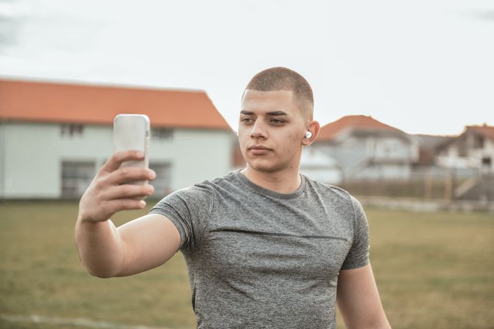 Young white guy taking selfie while exercising at park