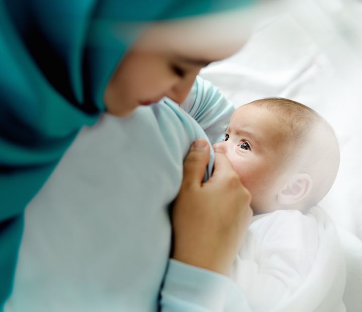 Muslim mother is breast-feeding her baby