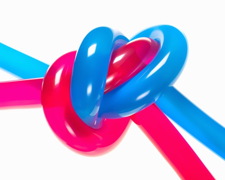 Bright red and blue balloons knotted together on bright white background