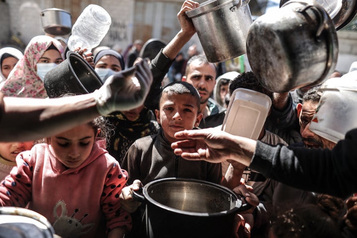 Palestinian people with empty pots receive food distributed by charity as Gaza faces a hunger crisis amid an aid blockade due to the ongoing Israeli offensive on Feb. 29 in Deir al Balah, central Gaza.