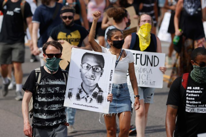 FILE - Demonstrators carry placards as they walk down Sable Boulevard during a rally and march over the death of Elijah McClain in Aurora, Colo., June 27, 2020. (AP Photo/David Zalubowski, File)