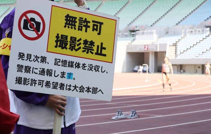 木南記念陸上の会場でスタッフが手に持つ無許可での撮影禁止を示す看板＝2020年10月24日、大阪・ヤンマースタジアム長居