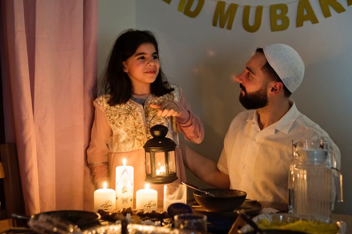 North-American muslim father and daughter eating Iftar at Ramadan. Traditional Lebanese and moroccan food on the table. Candle light. Horizontal waist up indoors shot. This was taken in Quebec, Canada.