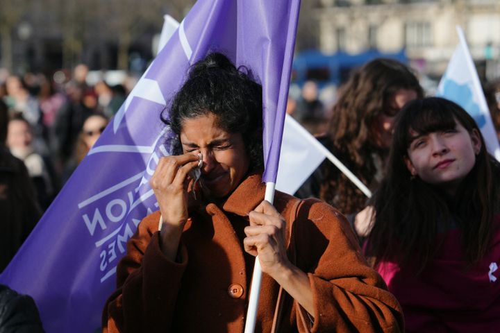 A woman sheds tears as she holds a flag of the "Fondation des Femmes" women's rights group at the Place du Trocadero in Paris on Monday.