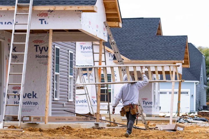 A man carries a ladder through new home construction in Trappe, Maryland, on Oct. 28, 2022.