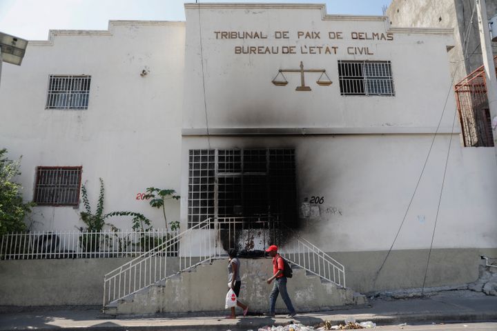 Pedestrians walk past a court building that was set on fire by gangs moments before in the Delmas 28 neighborhood of Port-au-Prince on Wednesday.