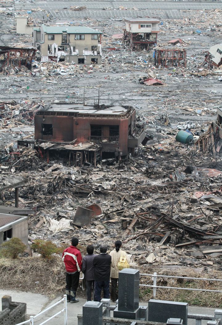 地震、津波、火災に襲われた自宅があった周辺を見つめる家族（2011年3月15日、岩手県大槌町）