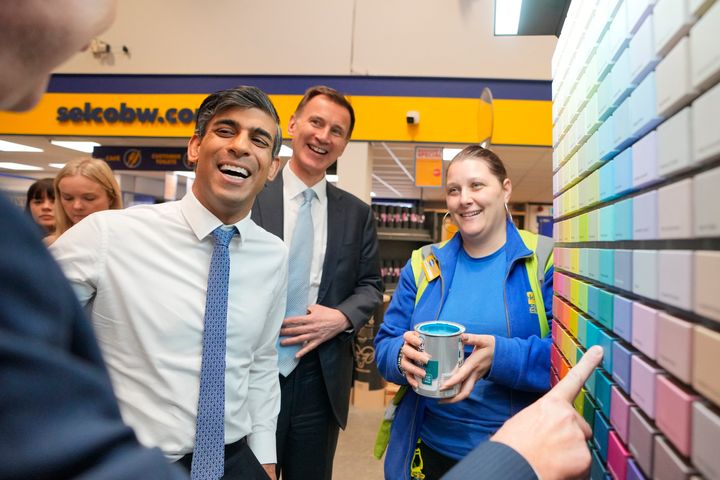 Rishi Sunak and Jeremy Hunt look at paint mixing charts during a visit to a builders warehouse.