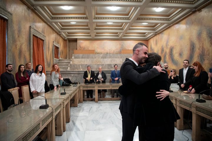 Ο δικηγόρος Αναστάσιος Σαμουηλίδης, αριστερά, αγκαλιάζει τον σύζυγό του, Έλληνα συγγραφέα Πέτρο Χατζόπουλο, ο οποίος χρησιμοποιεί το ψευδώνυμο Auguste Corteau, καθώς παρακολουθούν οι καλεσμένοι, μετά το γάμο τους στο Δημαρχείο Αθηνών, την Πέμπτη 7 Μαρτίου 2024. (AP Photo/Michael Varaklas)