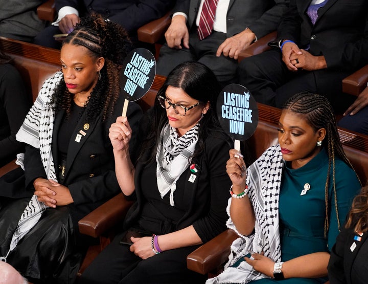 Reps. Rashida Tlaib (D-Mich.) and Rep. Cori Bush (D-Mo.) hold up signs reading "Lasting Ceasefire Now" as President Joe Biden delivers his State of the Union address to a joint session of Congress on Capitol Hill on March 7, 2024. 