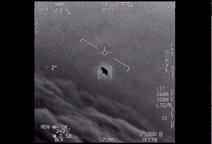 In an image from video provided by the Department of Defense labelled "Gimbal," an unexplained object is seen at center as it soars high along the clouds, traveling against the wind. (Department of Defense via AP)