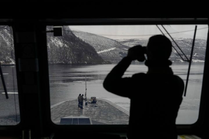 A French sailor uses binoculars to scan the area as others stand on the bow of the French navy frigate Normandie during a docking maneuver in a Norwegian fjord, north of the Arctic circle, on March 8.