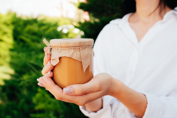 Jar of peanut butter in hand. Chocolate paste. Small business. Eco packaging. Place for the inscription of the company and production. Healthy snack. Food.