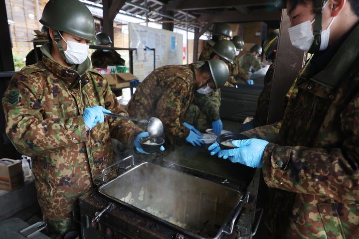 炊き出しの味噌汁を配る自衛隊員ら