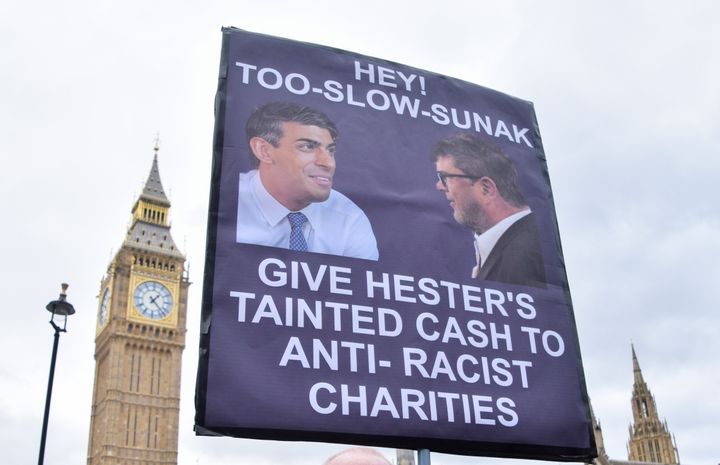 A protester holds a placard referencing Tory donor Frank Hester's recent comments, during a demonstration in Parliament Square. 